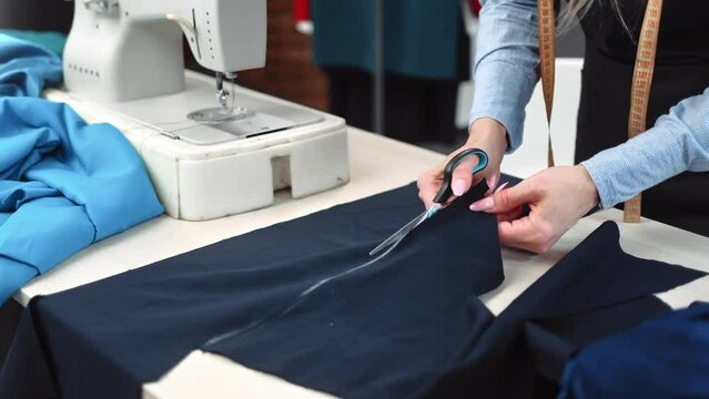 Female seamstress hands cutting textile pattern details use scissors working at tailoring atelier