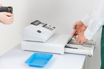 レジ打ちをする・操作する店員・従業員・バイトの男性と買い物に来た女性
