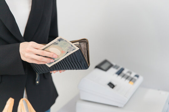 コンビニ・スーパーのレジで会計を現金・紙幣で支払う女性の手元
