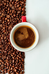 Espresso in a cup on a background of coffee beans on a white background.
