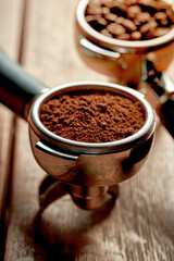 Ground coffee and beans in a holder from a coffee machine on a wooden background. Coffee concept