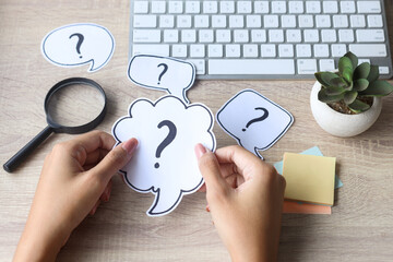Hands holding question mark at office desk. FAQ concept. Working with clients. Troubles in work.