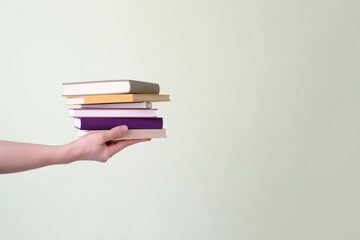 Fototapeta premium Hand holding some books on pastel background with copy space. Created with Generative AI Technology