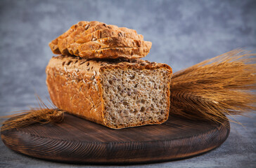 Freshly baked bread and wheat ears on rustic background. Toned.
