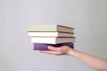 Fototapeta premium Hand holding some books on pastel background. Created with Generative AI Technology
