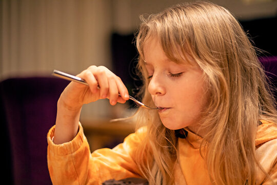 little girl happily eats a cake with a fork in a cafe. horizontal