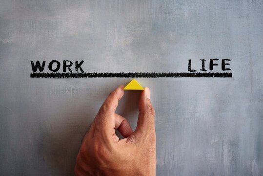 Hand holding wooden triangle with text WORK and LIFE. Work life balance concept