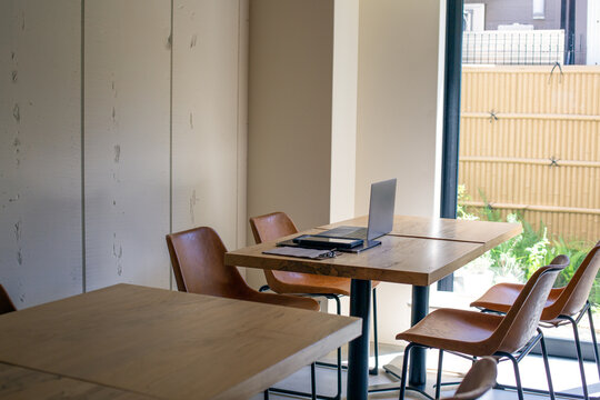 A restaurant with white walls and wooden tables and chairs.