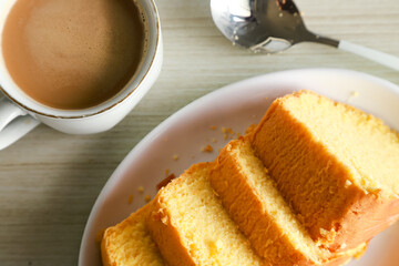 pieces of sponge cake or kue bolu served on a plate with a glass of coffee