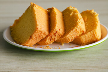 pieces of sponge cake or kue bolu served on a plate with a glass of coffee