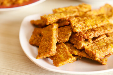 Tempe goreng or fried tempeh is served on a plate along with sambal