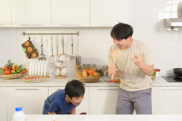 Happy Young Asian father and son making breakfast together. playful in kitchen at home