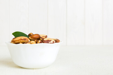 Fresh healthy Brazil nuts in bowl on colored table background. Top view Healthy eating bertholletia concept. Super foods