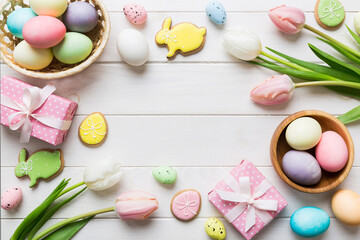 Easter frame with eggs, gift box and tulip on a colored background. The minimal concept. Top view Happy Easter composition. Card with a copy space of the place for the text