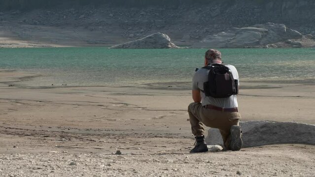 Man with camera in hand intent on taking a picture. Natural landscape. Video 4K