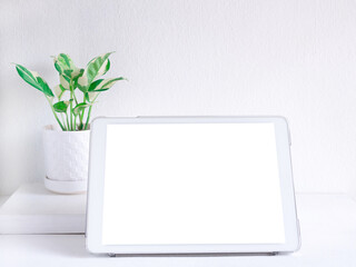 Mock-up tablet with blank screen, house plant on white table. Copy space for advertising of products, text, and design. Business and education concept..