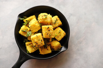 Indian chana Dal dhokla. Khaman dhokla is a famous dish of Gujarat. Made using rice, a healthy mix lentils and pulses, along with spices. garnished with coriander and fried chilies. Copy space