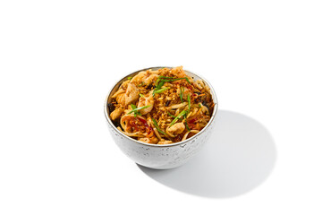 Asian fried noodles with chicken and vegetables isolated on white background Chinese fried noodles with chicken meat and shiitake mushrooms in ceramic bowl. Stir-fry udon with vegetables and meat