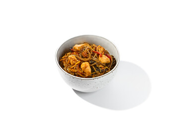 Asian fried buckwheat noodles with chicken and vegetables isolated on white background. Japanese fried noodles teriyaki in ceramic bowl. Fried on wok soba with chicken in minimal style. Wok menu.
