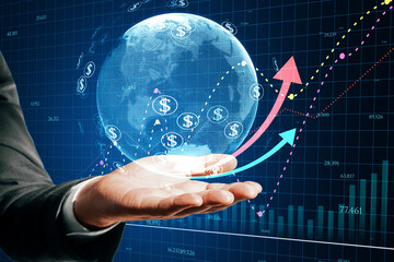 Close up of male hand holding glowing globe, financial arrows and money signs on blurry background. Digital world, cryptocurrency, online banking trade and technology concept.