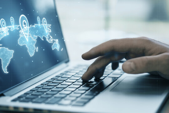 Close up of hand using laptop keyboard on desktop with glowing and with location pins on blurry background. GPS and navigation concept.