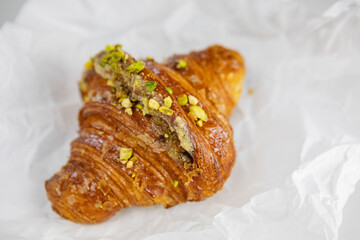 A delicious croissant with pistachios on parchment paper