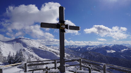 Eingeschneites Gipfelkreuz im Winter auf beschneitem Berg