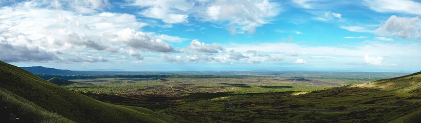Fototapeta na wymiar Panoramic shot of green landscapes under a cloudy sky
