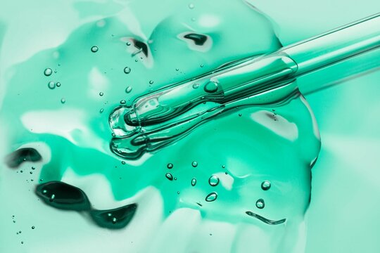 Liquid green gel or serum on blue glass of microscop background
