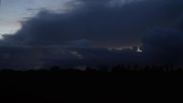 Time lapse of sunset with rolling clouds and silhouette treeline on countryside, Gloucestershire, UK