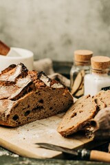 Vertical shot of a loaf and slices of fresh bread on a wooden board on a rustic background
