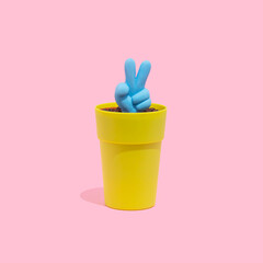 Blue peace, victory symbol icon growing from a small pot on a pastel pink background. Hand gesture, peace or victory concept.
