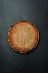 Kitchen round cutting board. Brown board. Kitchen utensils. On a dark background.