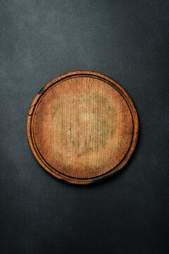 Kitchen round cutting board. Brown board. Kitchen utensils. On a dark background.