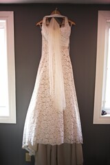 Vertical shot of a white wedding dress hanging from a wall