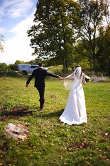 Vertical shot of the bride and groom in a green field