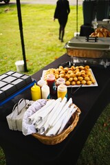 Vertical shot of sweet sauces and muffins on a black table in the middle of a green field