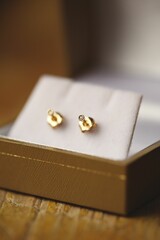 Vertical selective focus shot of gold earrings in jewelry box on blurry background