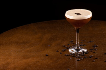 espresso martini cocktail in glass served under rubber holder with spilled coffee beans on table