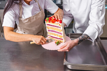 Fototapeta na wymiar Colombian Pastry Chef. Chef working together on a multi-tiered cake with natural strawberries.