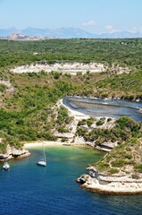 Vertical shot of the green shore and blue sea with boats. Bonifacio, Corsica. France.