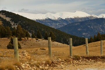 Row of wooden poles against the background of snow-covered mountains.