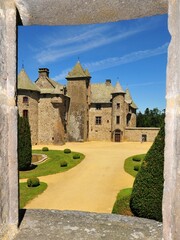 Fototapeta na wymiar Vertical view of the Chateau de Cordes Castle through a stone window in Orcival, France
