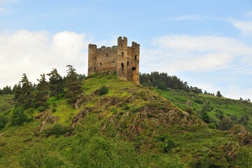 Fototapeta na wymiar Alleuze Castle on the hill surrounded by green vegetation. France.