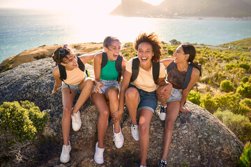 Female Friends With Backpacks On Vacation Taking A Break On Hike Through Countryside