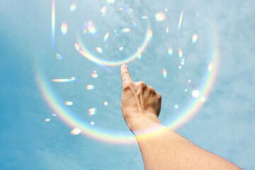 hand raised in the blue sky gesturing with the sunlight