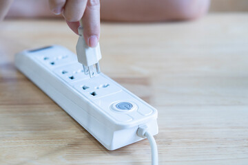 Closeup of a woman hand inserting a plug into electrical power strip.