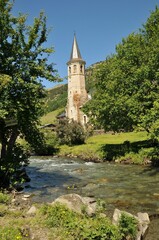 Fototapeta na wymiar River running through a lush green forest with a small church in the background