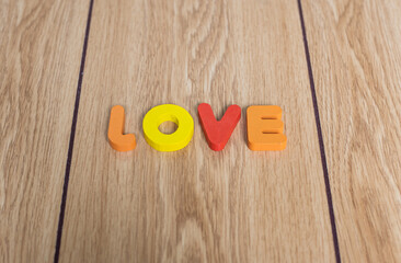 Closeup shot of colorful wording "LOVE" in capital letters on wooden background. Background picture of valentine theme. 