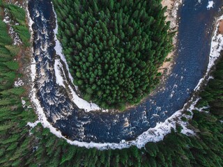 Fototapeta premium Aerial view of a river surrounded by trees and snow in Quebec, Canada